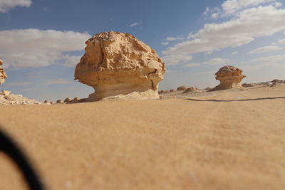 Surface level of rocks on sand against sky