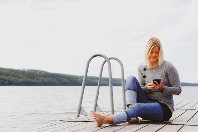 Young woman smiling while sitting by lake