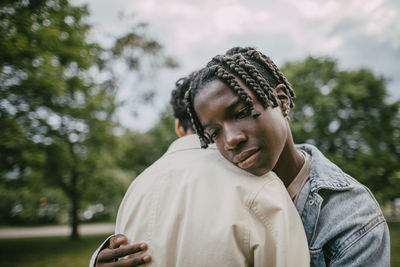 Braided hair boy hugging male friend at park
