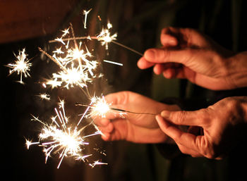 Hand holding firework display at night