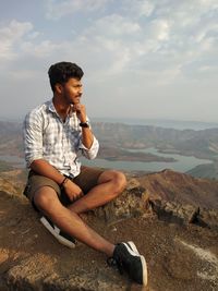 Young man looking at sea against sky