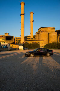 Cars on road by buildings against clear sky