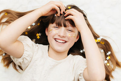 Portrait of a pretty girl with star-shaped sequins on her face. the girl smiles. fun holiday