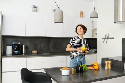 Side view of young woman standing in kitchen