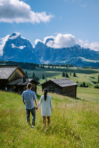 Rear view of people on field against mountains