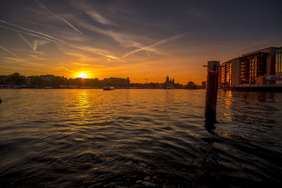 Scenic view of sea by buildings against sky during sunset