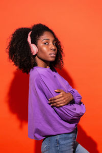 Portrait of young woman against orange background