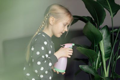 Side view of girl watering plant