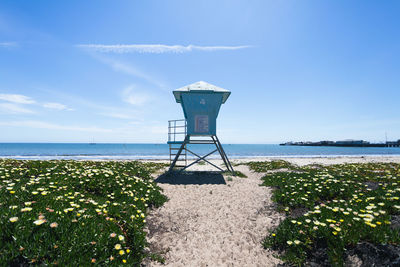 Lifeguard hut on beach against blue sky