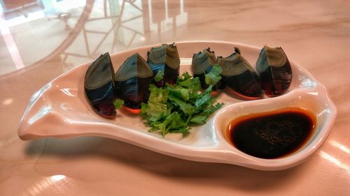 High angle view of century egg with coriander and sauce on table