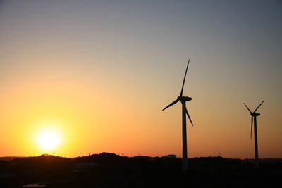 Silhouette windmills against sky during sunset