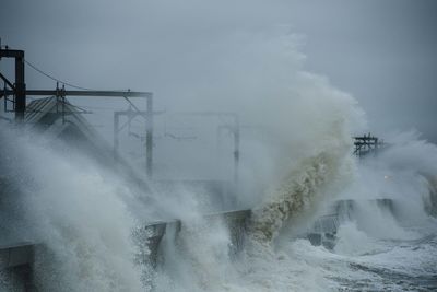 Waves splashing on shore against sky