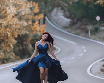 Young woman in blue dress walking on the road