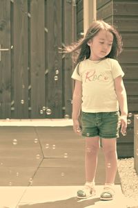 Full length of a smiling girl standing against wall