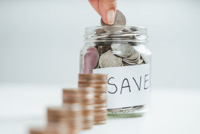 Close-up of hand holding jar against white background