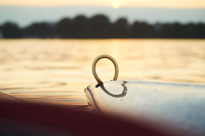 Close-up of silhouette metal by lake against sky during sunset