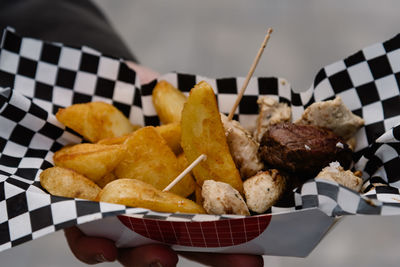 Cropped image of woman hand holding meat with french fries