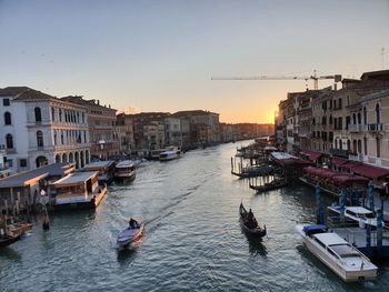 Boats in canal amidst buildings in city against sky