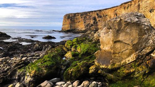 Scenic view of cliff by sea against sky