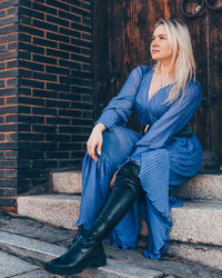 Full length of woman sitting against wall