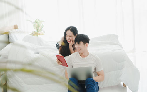 Smiling young woman using mobile phone while sitting at home