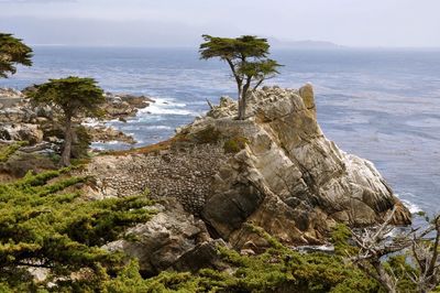 Scenic view of rocks by sea against sky