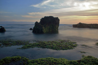 Scenic view of rocks in sea against sky during sunset