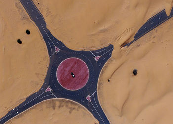 Drone shot of the roundabout in the desert. abandoned road. white car. dubai, united arab emirates.