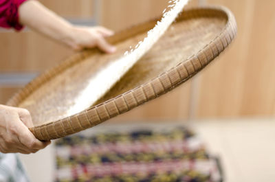 Cropped hand cleaning rice in wicker container