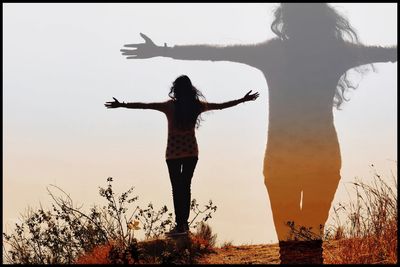 Full length of woman with arms raised standing against sky