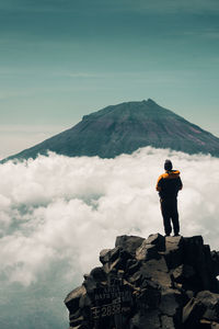 A man standing on rock at approximately 2800m above sea level facing to a mountain or strato volcano