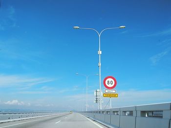 Road sign on bridge against blue sky