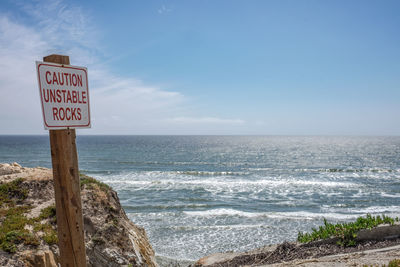 Sign board against sky on sunny day