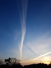 Low angle view of vapor trails against blue sky