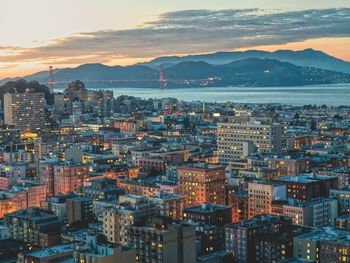 High angle view of illuminated city buildings against sky during sunset