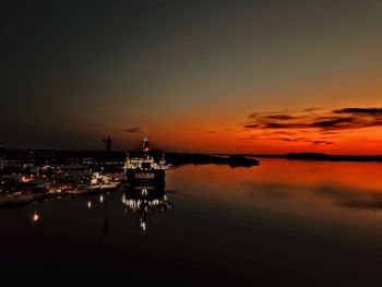 Illuminated temple over sea against sky during sunset