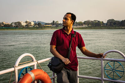 Full length of man standing on railing against sea