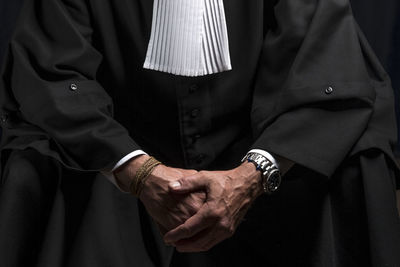 Midsection of lawyer standing against black background