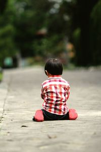 Rear view of boy kneeling on road