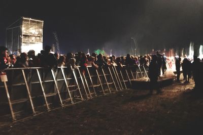 Group of people at music concert against sky at night