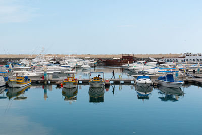 Boats moored at harbor against clear sky