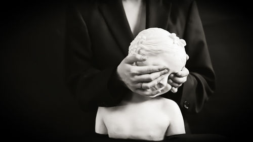 Midsection of woman holding ice cream against black background