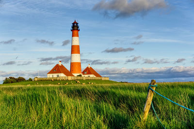 Lighthouse on field against sky