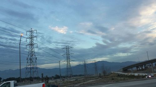 Electricity pylon against cloudy sky