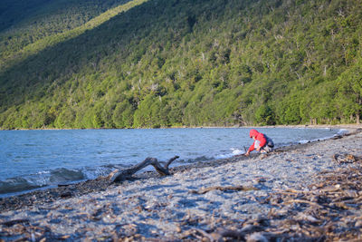 Boy sitting at beach against mountain