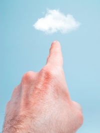 Close-up of human hand against sky