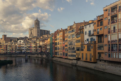 Buildings by river against sky