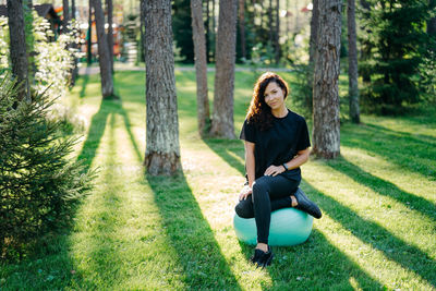 Portrait woman sitting on fitness ball in park