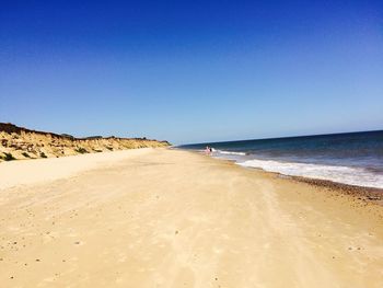 View of beach against clear blue sky