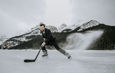 Hockey player in suit stops fast kicking up frozen spray on lake